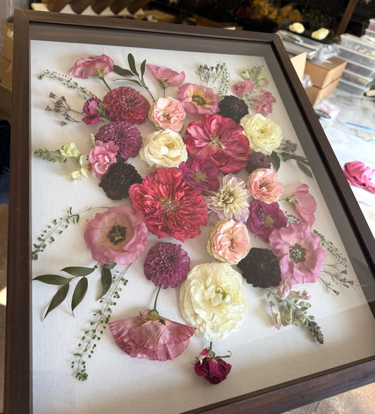Framed arrangement of pressed flowers with a white background